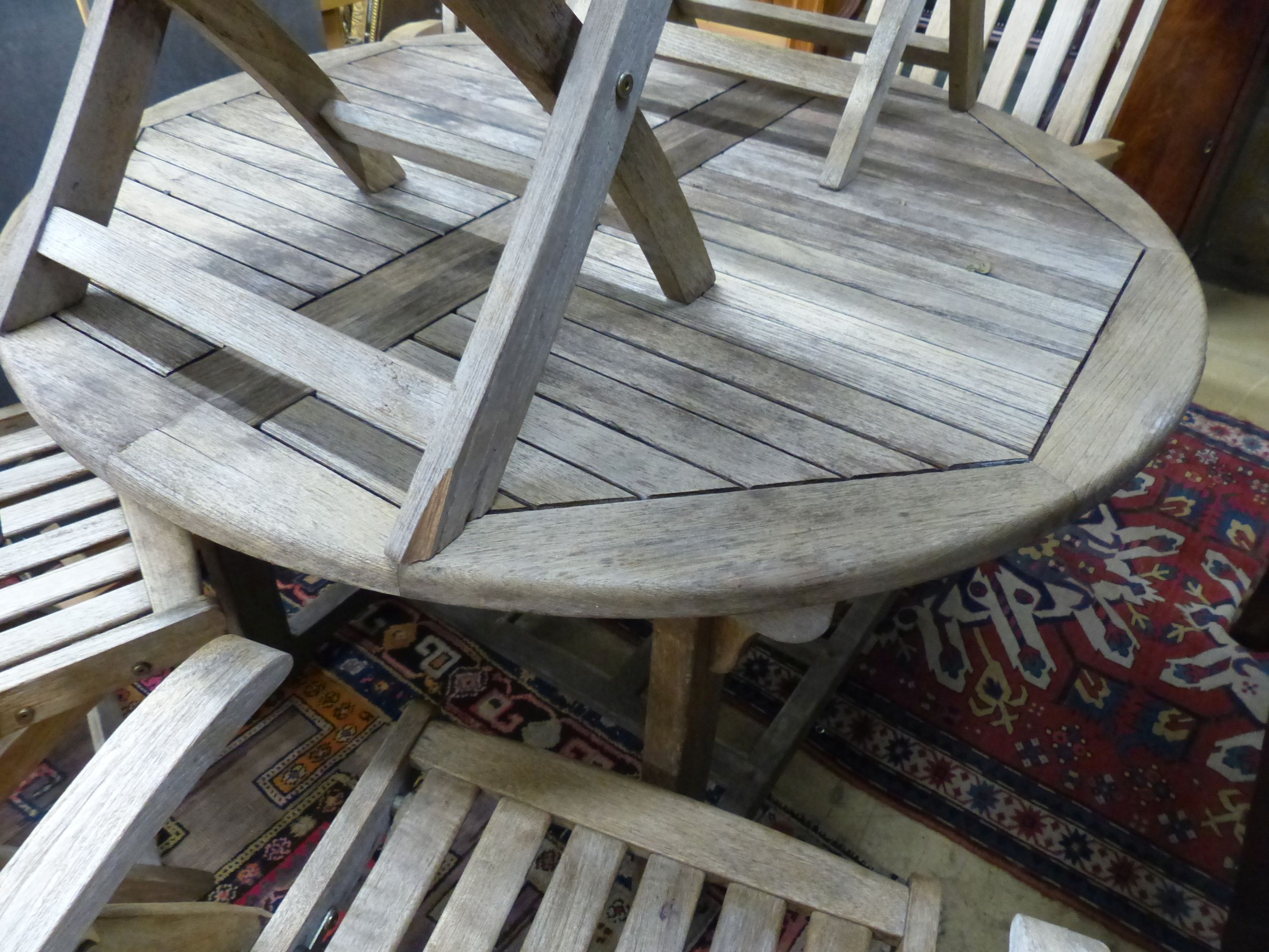 A circular weathered teak extending garden table, 180cm extended, W.120cm H.70cm and six folding garden armchairs